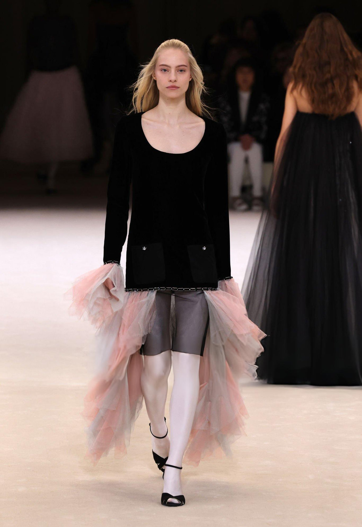 Model wearing Chanel Spring/Summer 2024 Haute Couture pink tulle ballet skirt over white tights with black ballet flats and black velvet top on runway