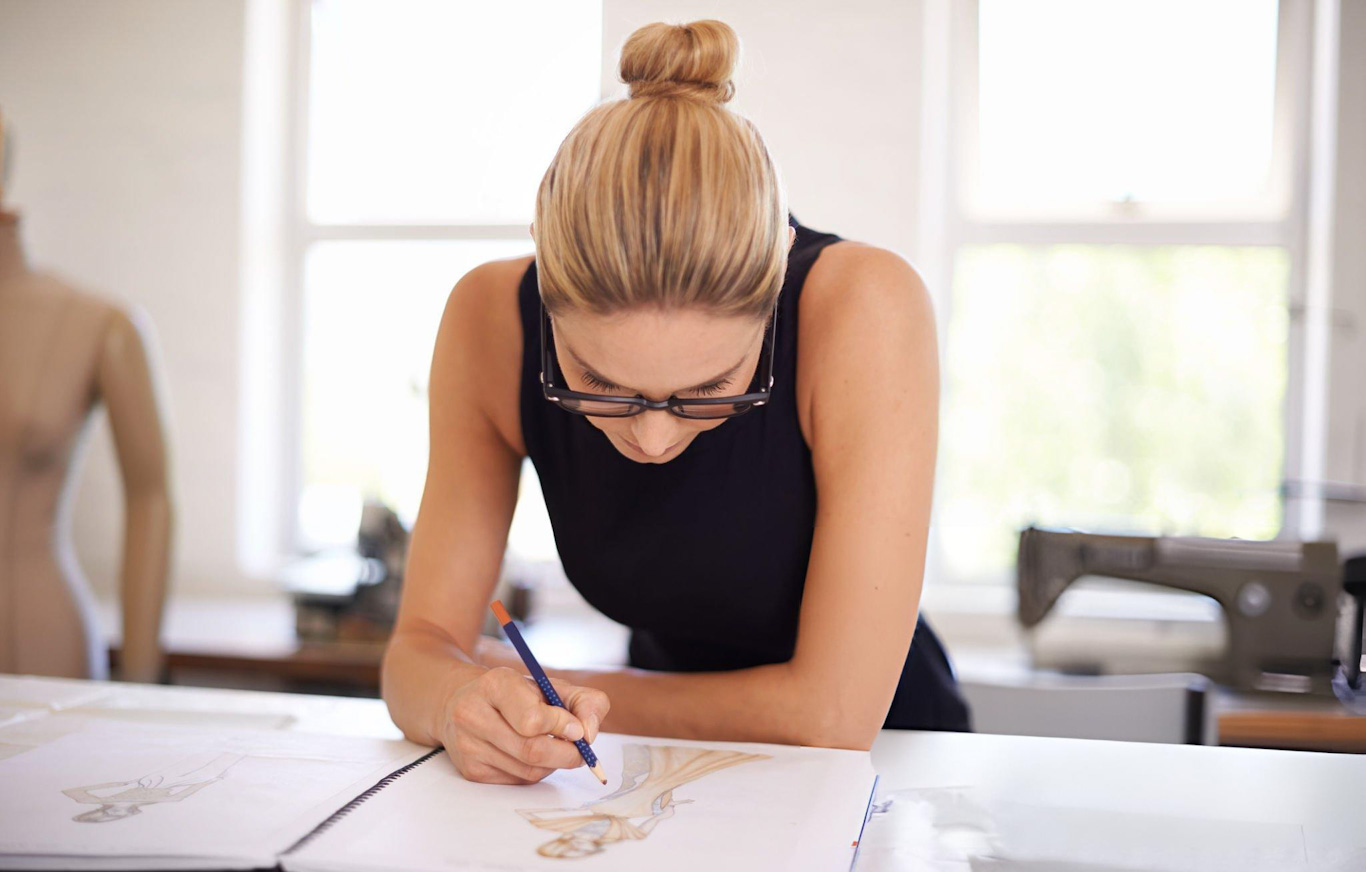 Fashion designer sketching clothing design in studio.