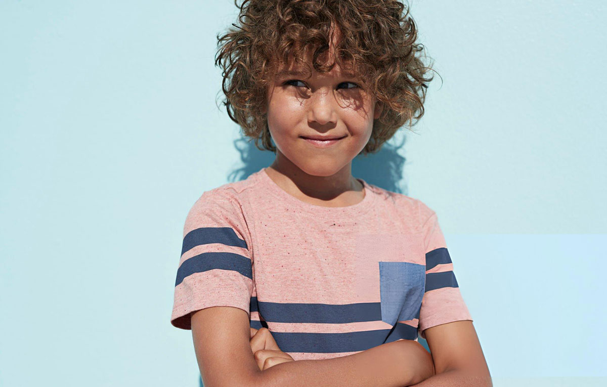 Smiling child with curly hair in striped shirt.