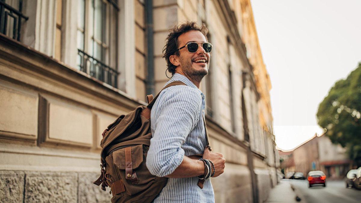 Smiling man with backpack in city street