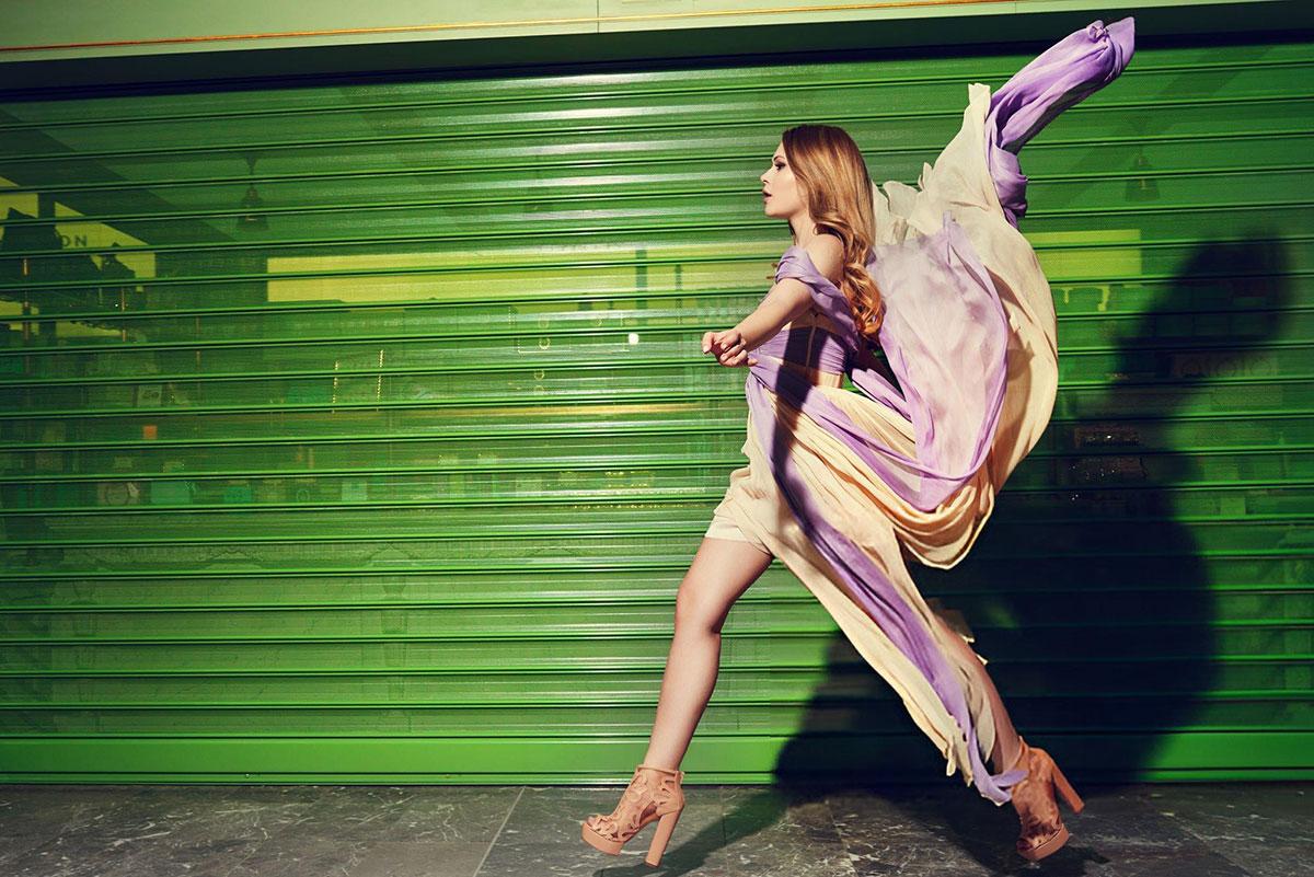 Woman in flowing dress, green background.