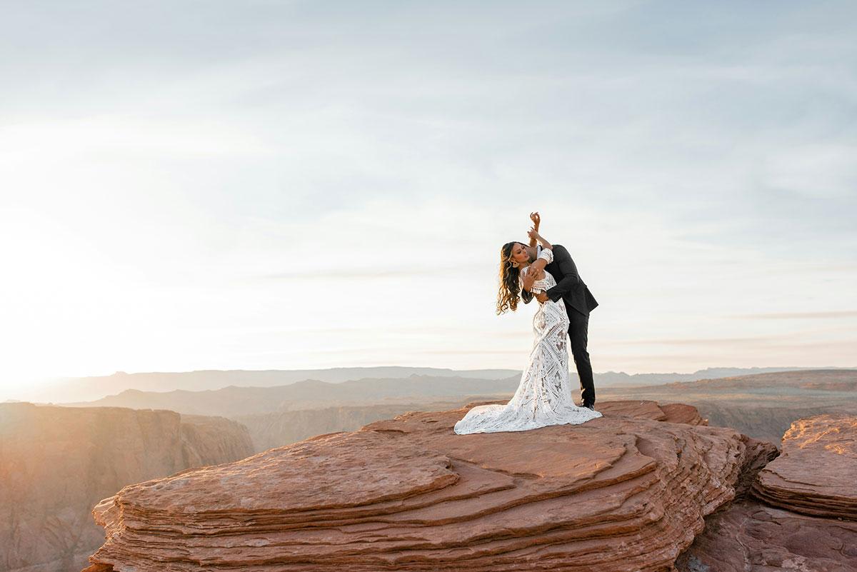 Couple embracing on scenic cliff at sunset.