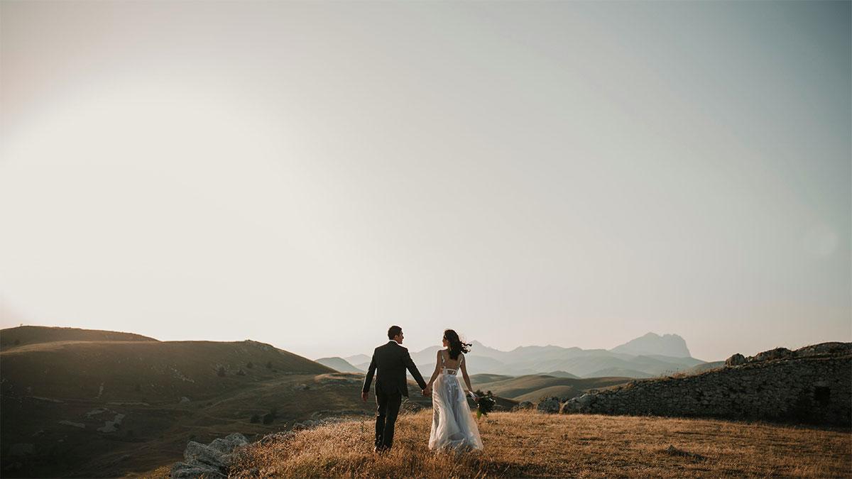 Couple holding hands in scenic landscape.