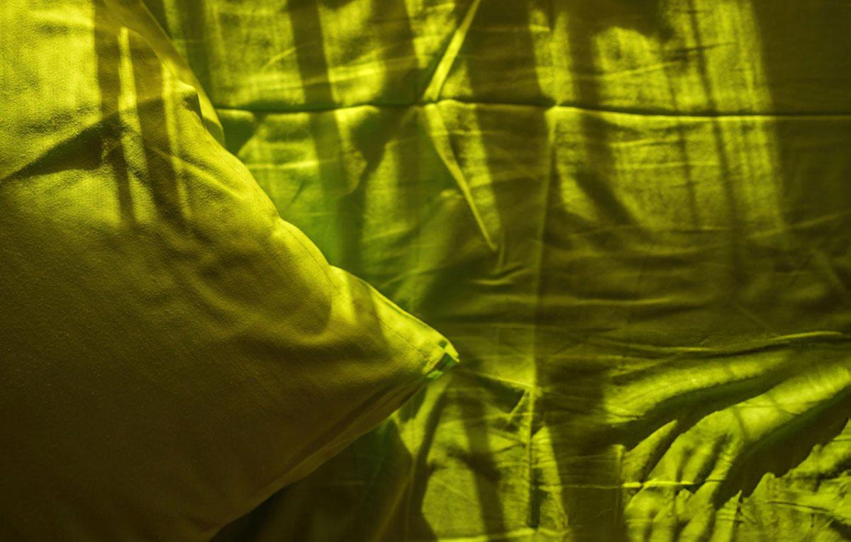 Sunlit green pillow and bed sheets.