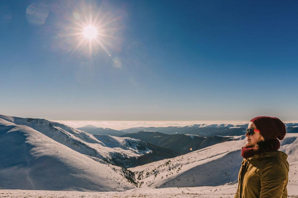 Woman in winter clothing on snowy mountain landscape.