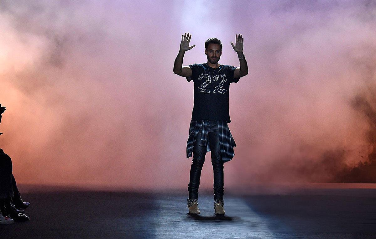Man standing on stage with raised hands.