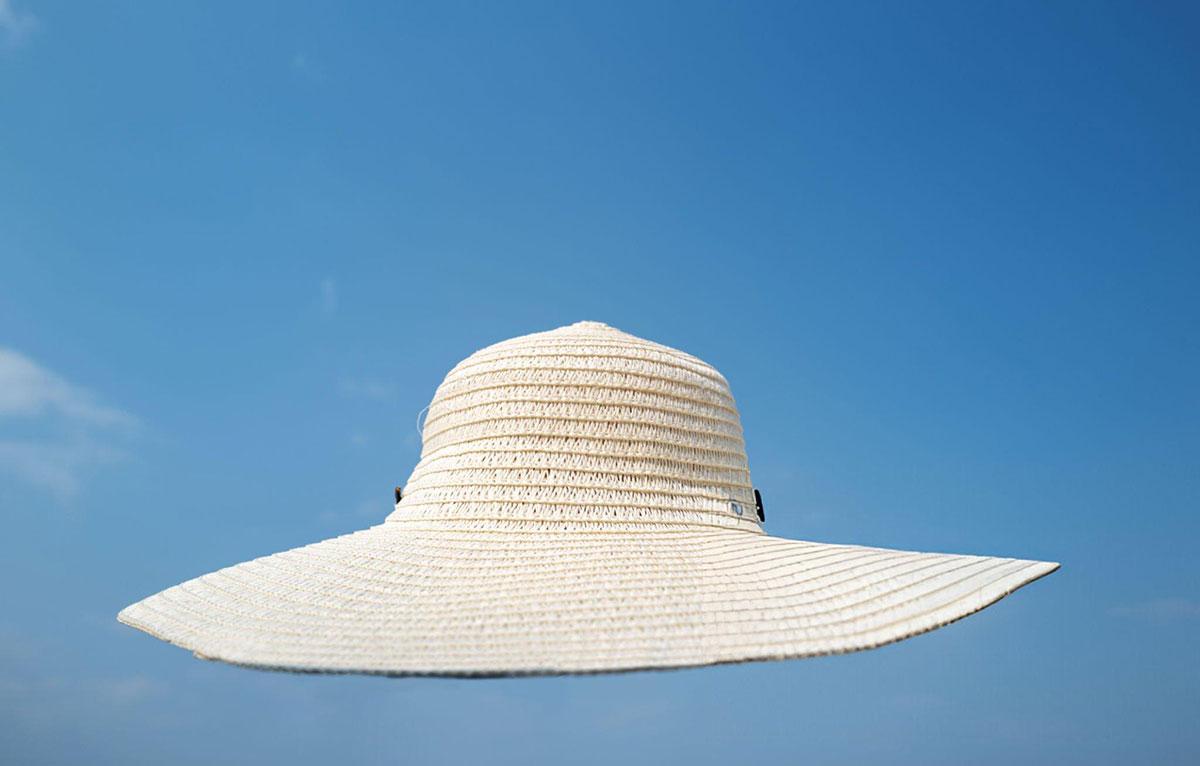 Wide-brimmed sun hat against clear blue sky.