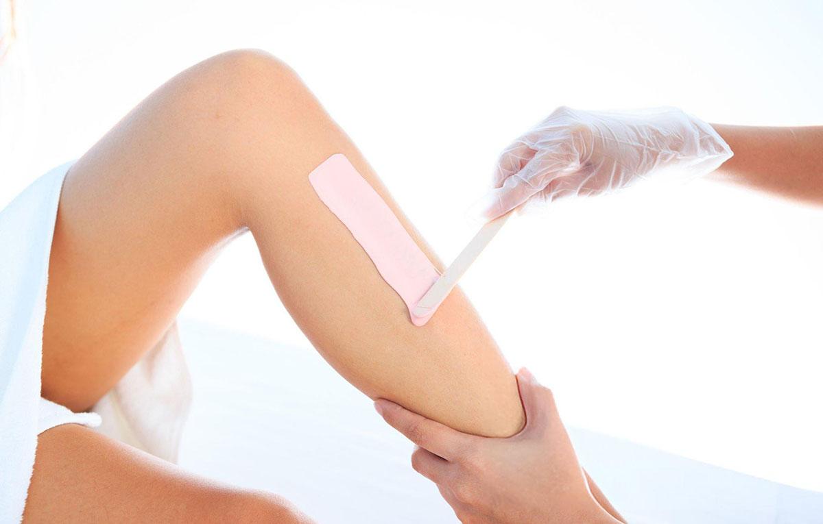 Person applying wax to leg for hair removal.