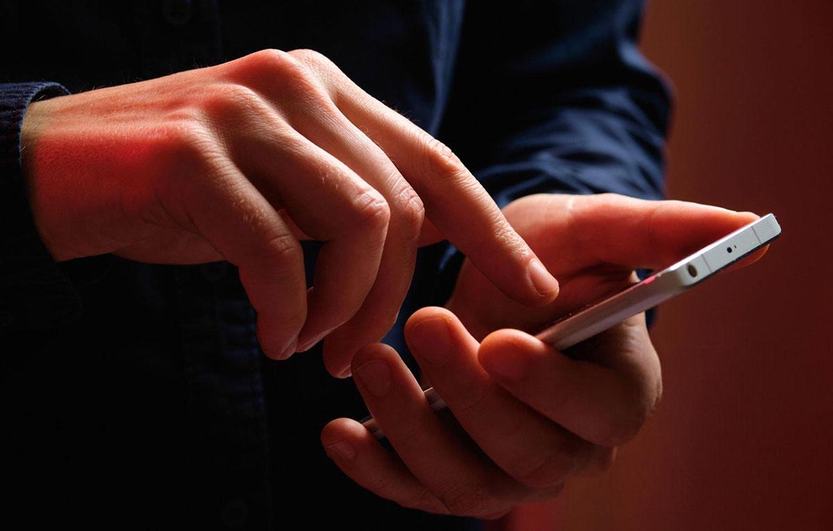 Hands using smartphone, touching screen gently.