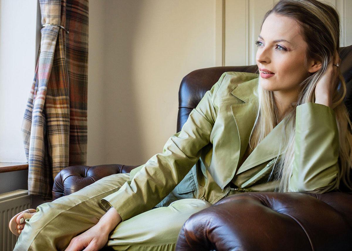 Woman in green suit sitting on leather chair.