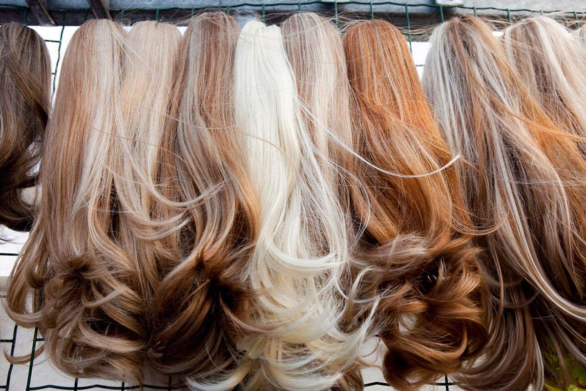Assorted wigs on display with different shades.