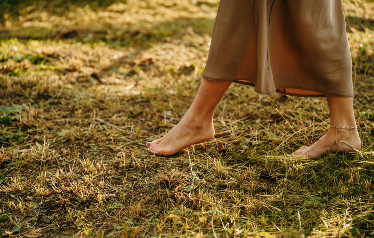 Barefoot woman walking on grass with ankle bracelet