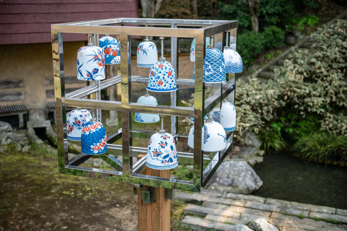 Traditional Nabeshima ware porcelain pieces with blue and white patterns displayed outdoors in Okawachiyama village, representing the premium kintsugi pottery that generates 80 million yen in five-day festival sales