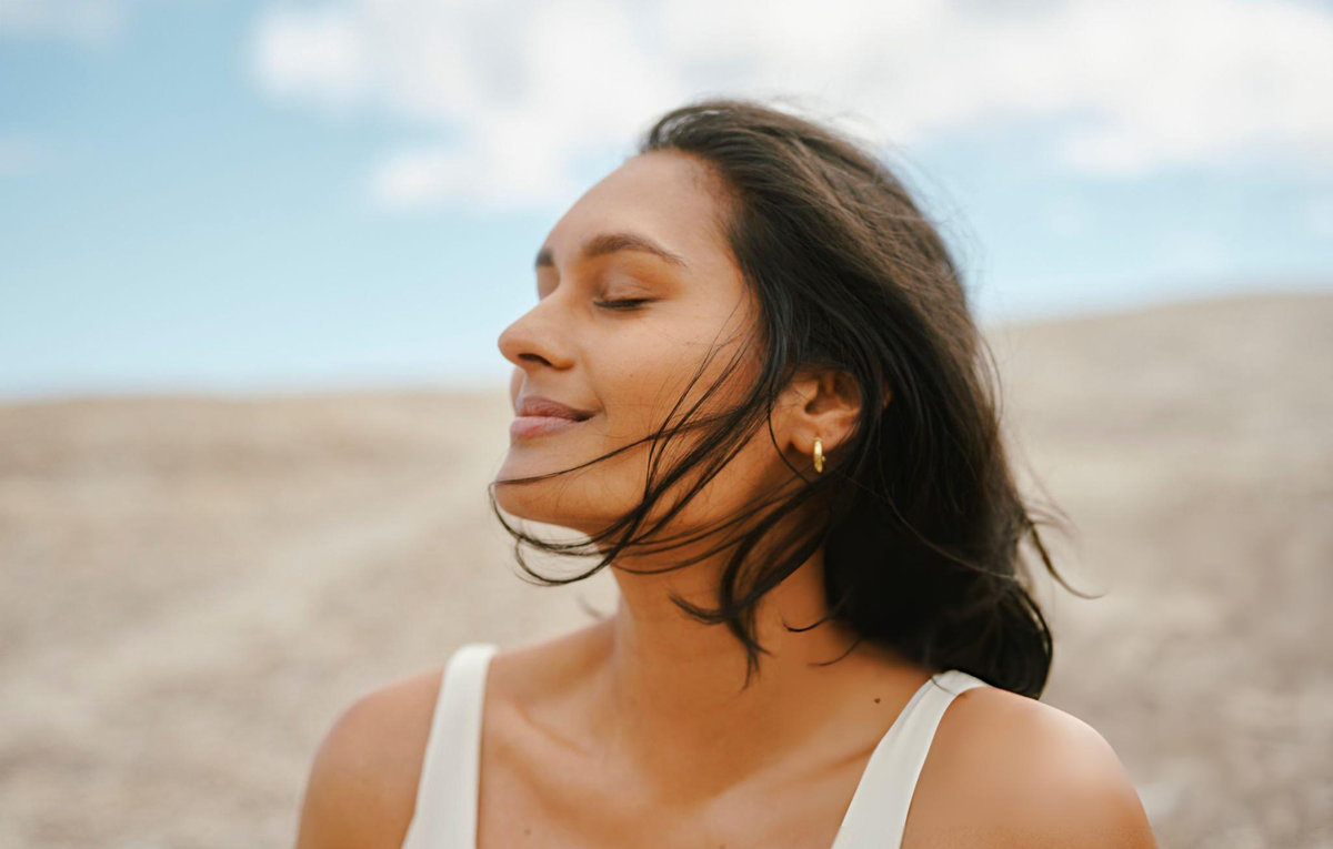 Woman with radiant natural skin outdoors embodying conscious luxury approach to inner health and holistic wellness lifestyle