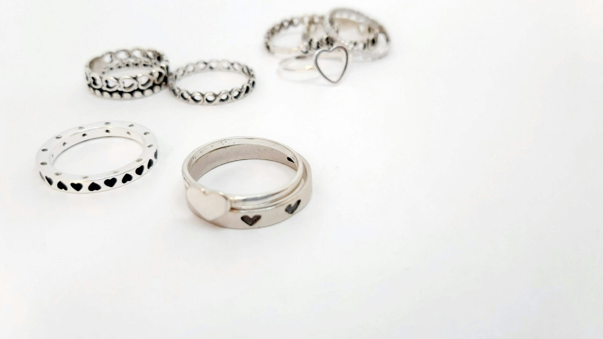 Collection of modern heart engagement rings in silver showing various contemporary designs including heart-shaped stones, heart cutout bands, and minimalist heart patterns on white background