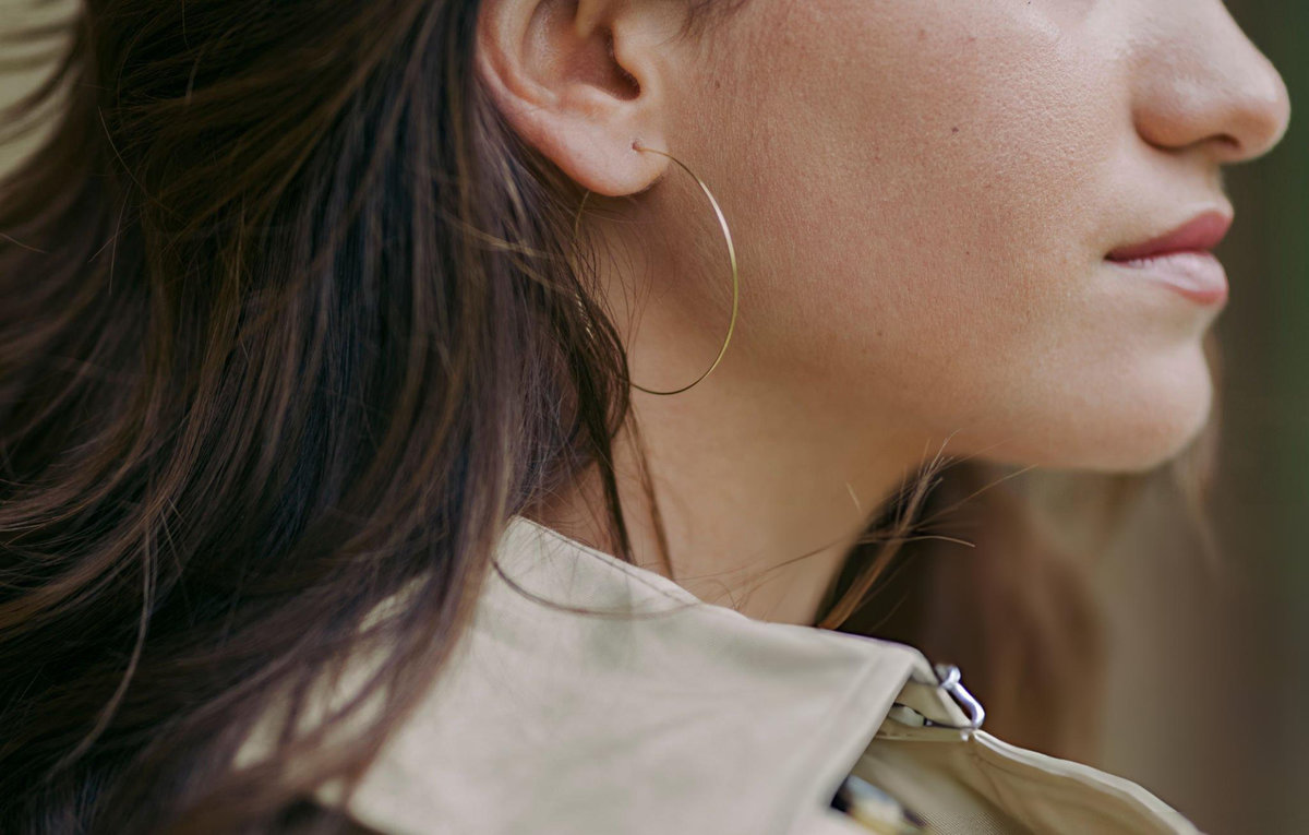 Woman wearing simple minimalist gold hoop earring demonstrating timeless sustainable jewellery design for everyday versatile styling
