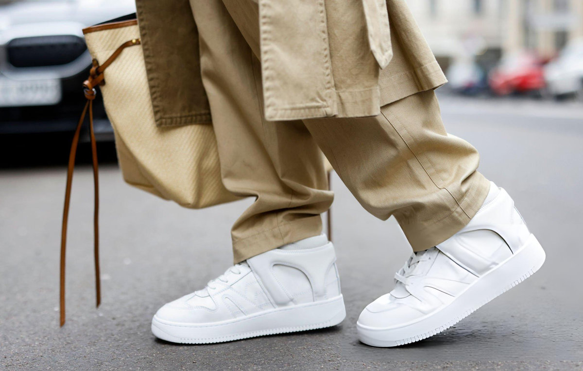 Model wearing white Isabel Marant sneakers with relaxed tailoring and cream jacket, demonstrating how luxury sneakers transition between casual and polished styling