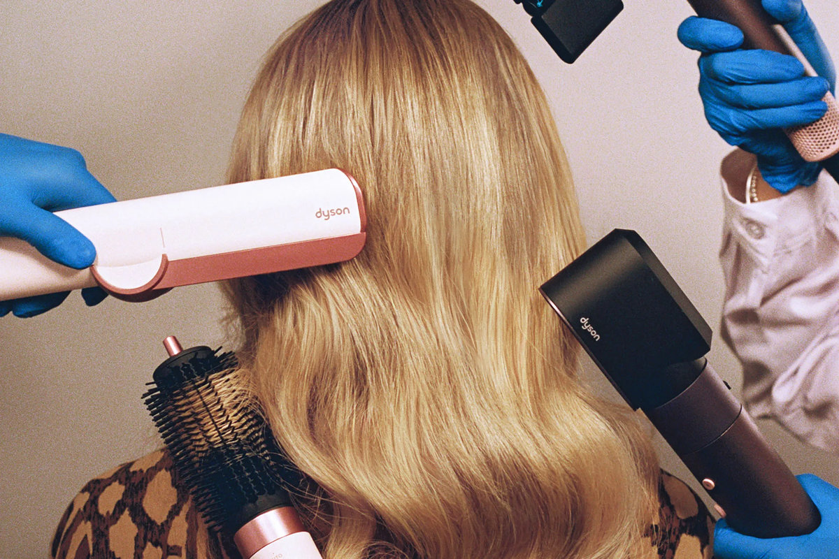 Professional hairstylist using Dyson hair dryer technology on blonde hair demonstrating modern heat styling techniques and equipment