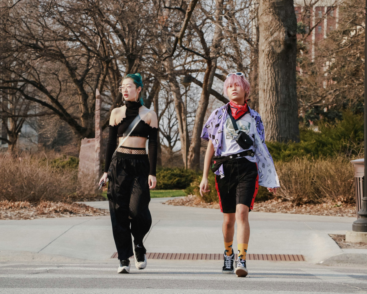 Two people with coloured hair wearing alternative street style outfits with layered accessories, printed shirts and bold sock styling