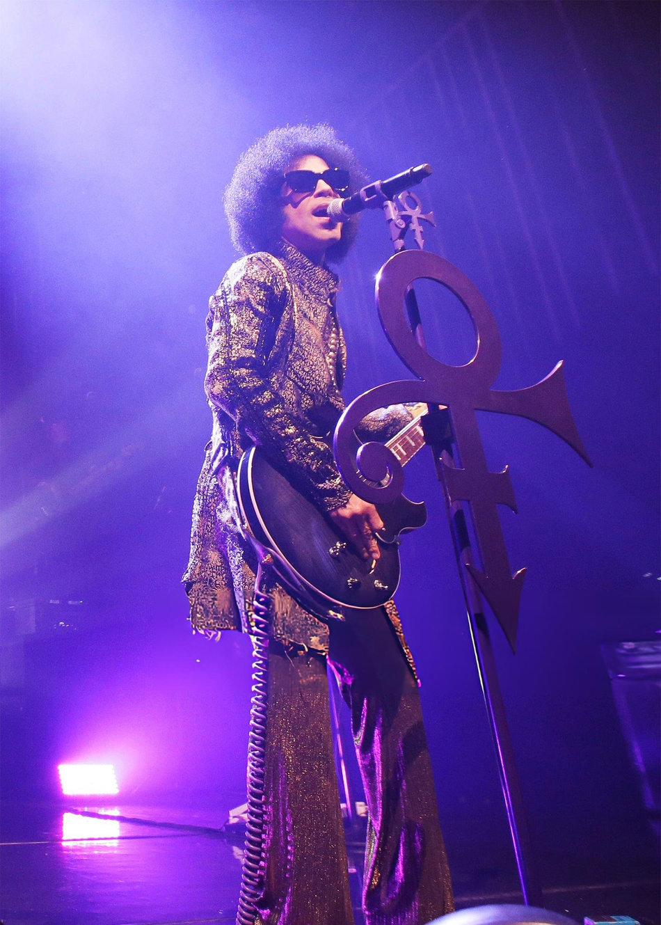 Prince on stage with an afro playing guitar during the HitnRun tour at The Fox Theatre in Detroit 2015