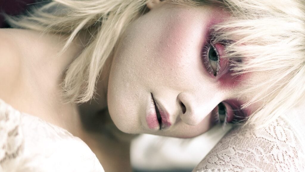 Close-up portrait of a woman with striking makeup and blonde hair, emphasizing artistic expression.